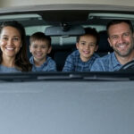 A family smiles confidently in their car, protected by the right insurance coverage.